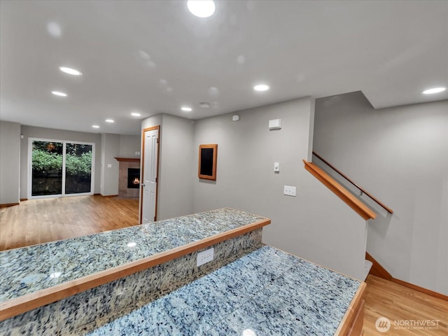 interior space featuring recessed lighting, wood finished floors, baseboards, and a tiled fireplace