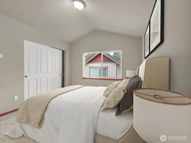 carpeted bedroom with lofted ceiling and baseboards