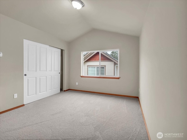 unfurnished bedroom with vaulted ceiling, carpet, baseboards, and a closet