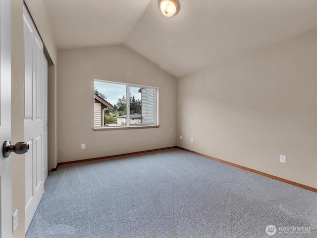 unfurnished bedroom with lofted ceiling, carpet floors, baseboards, and a closet