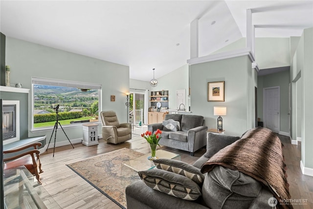 2835 Aspen Shores Dr, East Wenatchee, WA 98802 - living area featuring high vaulted ceiling, a glass covered fireplace, wood finished floors, and baseboards
