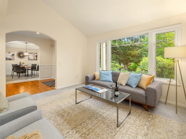living room with arched walkways, lofted ceiling, wainscoting, and baseboards