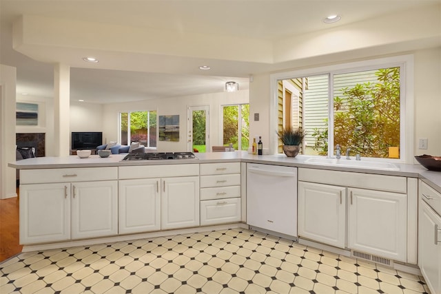 kitchen featuring dishwasher, a sink, light flooring, white cabinets, and open floor plan