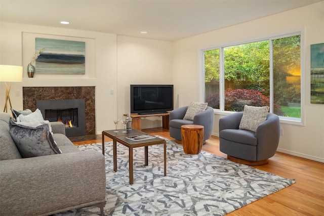 living area with a premium fireplace, wood finished floors, recessed lighting, and baseboards
