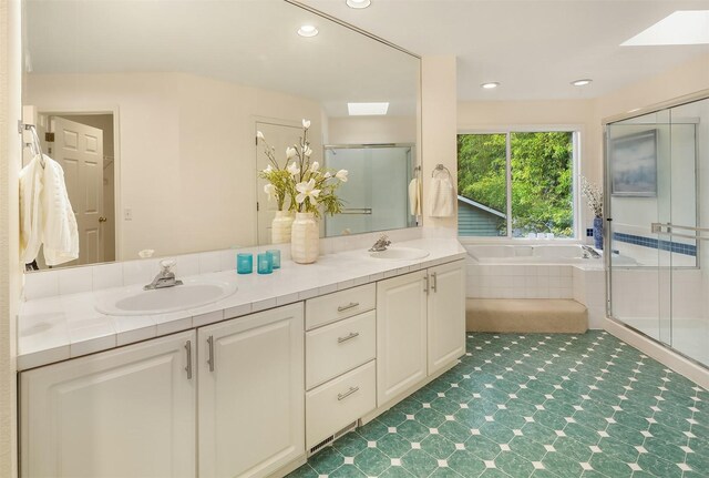 full bathroom with a shower stall, double vanity, a garden tub, recessed lighting, and a skylight