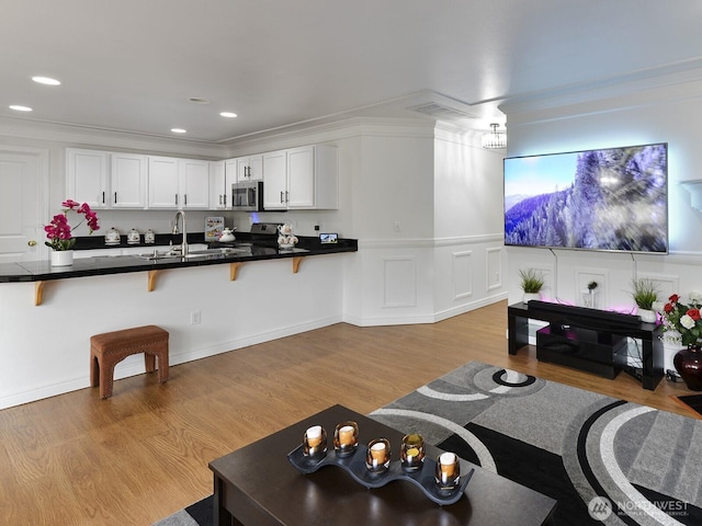 living area featuring light wood finished floors, recessed lighting, and crown molding