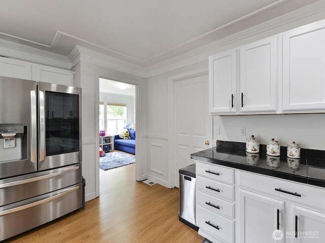 kitchen featuring stainless steel fridge, white cabinetry, light wood finished floors, and crown molding