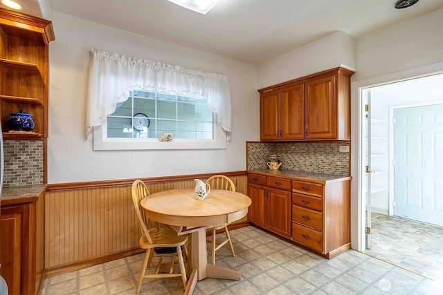 116 E 4th St, Centralia, WA 98531 - kitchen with a wainscoted wall, brown cabinetry, light flooring, decorative backsplash, and wood walls