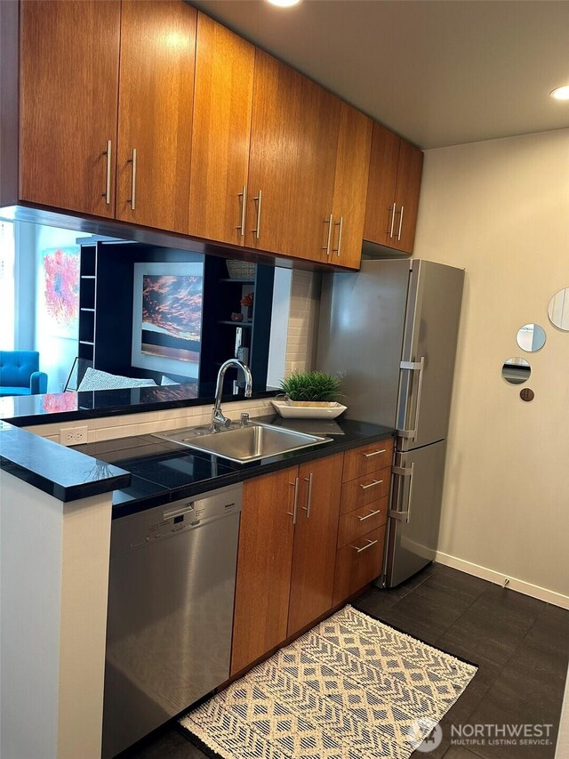 2721 1st Ave Unit 103, Seattle, WA 98121 - kitchen featuring stainless steel appliances, a sink, brown cabinets, dark countertops, and baseboards