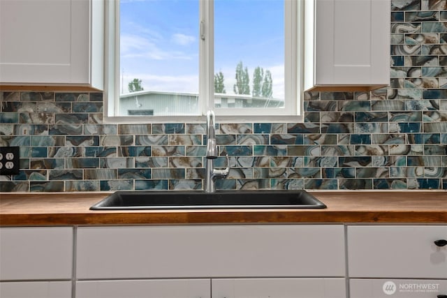 1118 W Wishkah St, Aberdeen, WA 98520 - kitchen view of a sink, white cabinetry, backsplash, and butcher block countertops