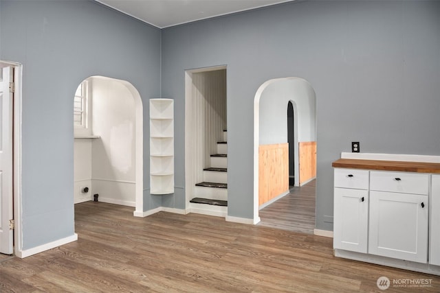 1118 W Wishkah St, Aberdeen, WA 98520 - empty room with light wood-style floors, arched walkways, baseboards, and stairway