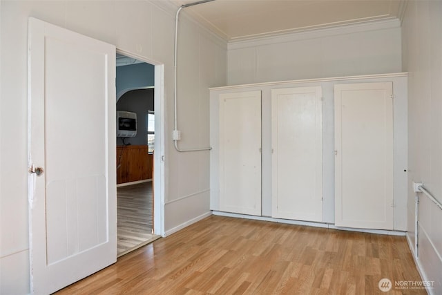 1118 W Wishkah St, Aberdeen, WA 98520 - unfurnished bedroom with light wood finished floors, crown molding, a decorative wall, a closet, and arched walkways