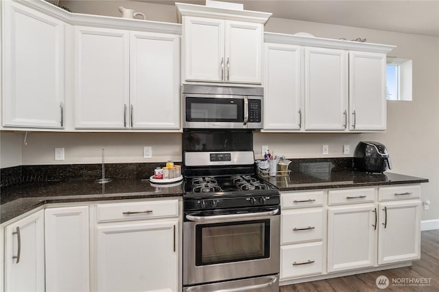18410 20th Avenue Ct E, Spanaway, WA 98387 - kitchen featuring appliances with stainless steel finishes, white cabinets, dark stone counters, and wood finished floors