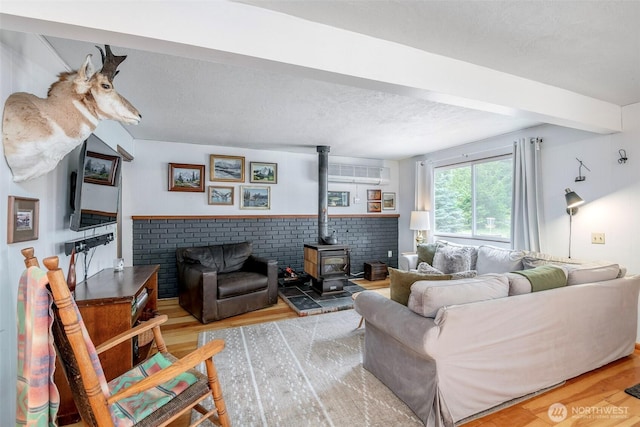 100 Aspen Ln, Packwood, WA 98361 - living room featuring wood finished floors, a wood stove, beam ceiling, a textured ceiling, and a wall mounted air conditioner