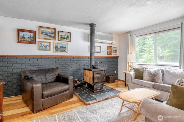 100 Aspen Ln, Packwood, WA 98361 - living area featuring wood finished floors, an AC wall unit, a wood stove, and a textured ceiling