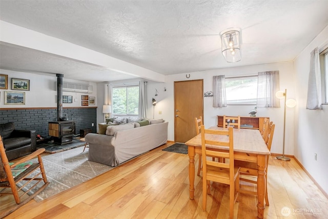 100 Aspen Ln, Packwood, WA 98361 - dining area featuring light wood-style floors, a wood stove, a textured ceiling, and baseboards