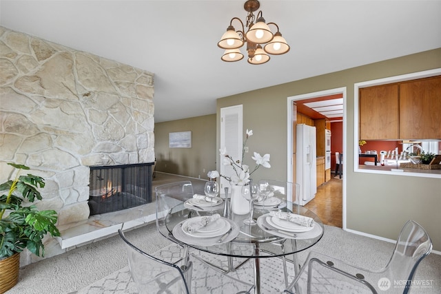 327 Priest Point Dr NW, Tulalip, WA 98271 - carpeted dining space with a stone fireplace, baseboards, and a chandelier