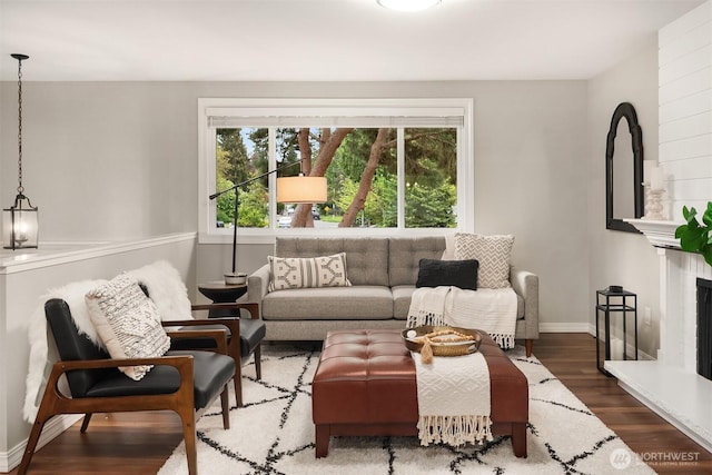 living room featuring wood finished floors, baseboards, and a fireplace with raised hearth