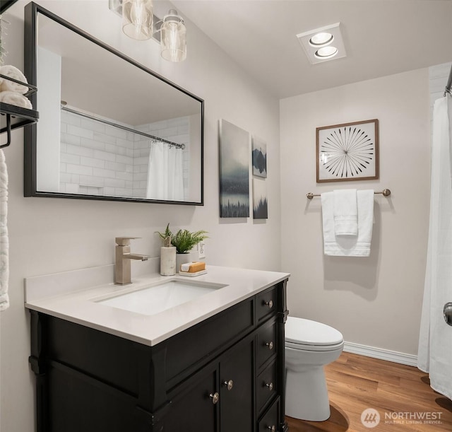 bathroom featuring wood finished floors, vanity, toilet, and baseboards