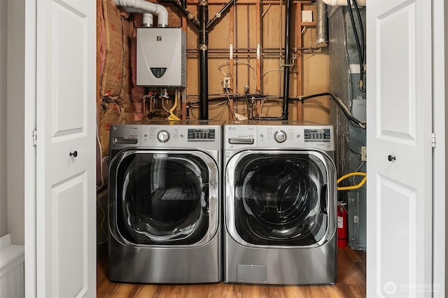 laundry area featuring washer and clothes dryer, tankless water heater, and wood finished floors
