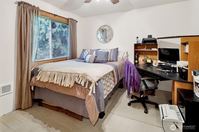 carpeted bedroom with a desk and ceiling fan