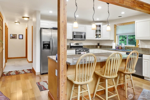 kitchen featuring stainless steel appliances, tile countertops, a kitchen bar, white cabinets, and recessed lighting