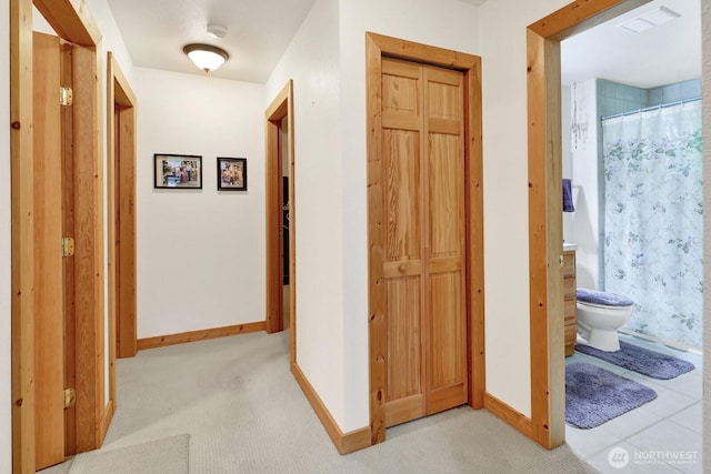 corridor featuring baseboards and light carpet