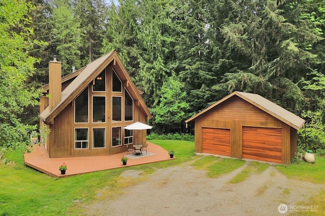 view of outbuilding with dirt driveway, an outdoor structure, and a view of trees