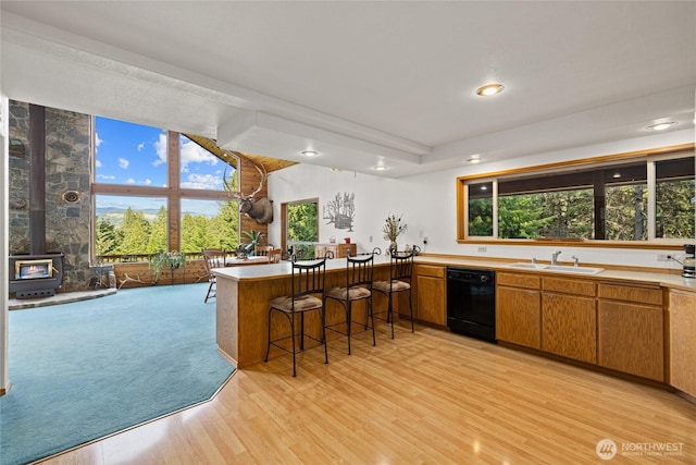 1101 Emerick Rd, Cle Elum, WA 98922 - kitchen with black dishwasher, a sink, light wood-type flooring, a wood stove, and a peninsula