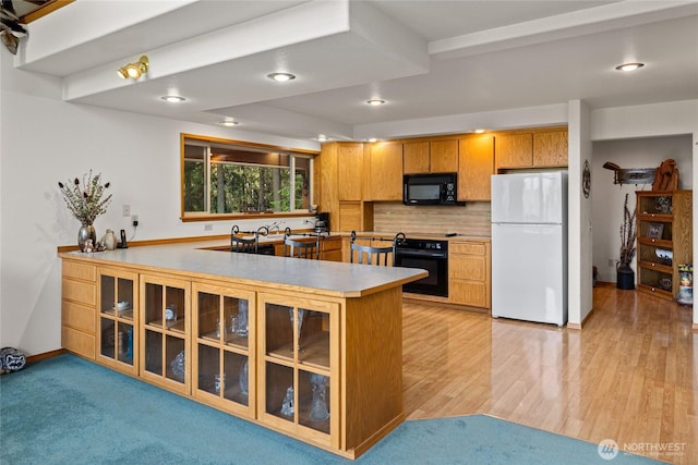 1101 Emerick Rd, Cle Elum, WA 98922 - kitchen featuring black appliances, backsplash, a peninsula, glass insert cabinets, and light countertops