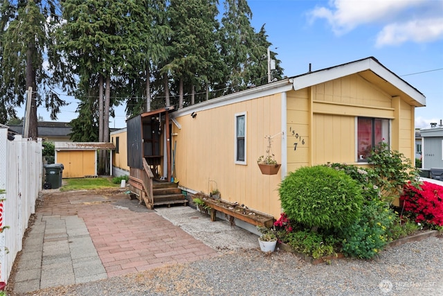 15016 W Thorne Ln SW Unit 7, Lakewood, WA 98498 - view of front of house featuring fence, a patio area, an outbuilding, and a storage shed