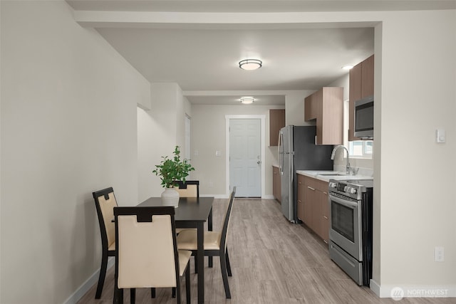 1319 E 56th St, Tacoma, WA 98404 - kitchen with appliances with stainless steel finishes, light countertops, light wood-style floors, and a sink