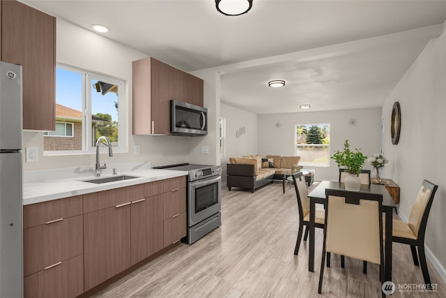 1319 E 56th St, Tacoma, WA 98404 - kitchen with stainless steel appliances, a sink, modern cabinets, light wood-type flooring, and open floor plan