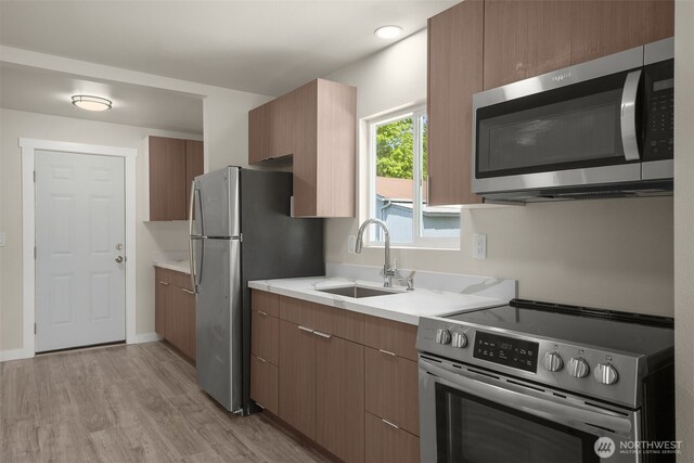 1319 E 56th St, Tacoma, WA 98404 - kitchen featuring stainless steel appliances, a sink, light wood-style floors, and light countertops