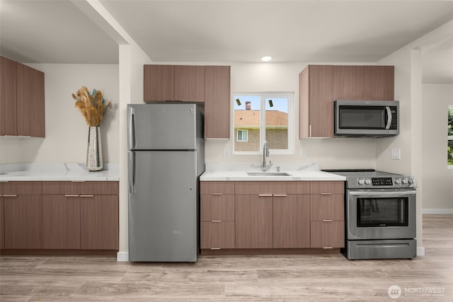 1319 E 56th St, Tacoma, WA 98404 - kitchen featuring appliances with stainless steel finishes, a sink, light countertops, modern cabinets, and light wood-type flooring