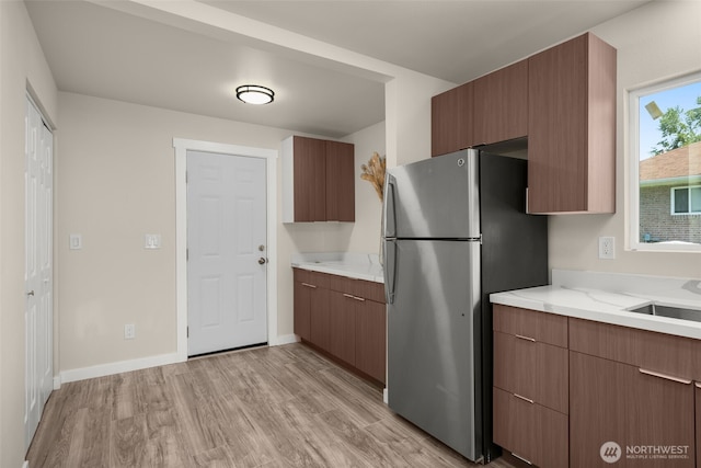 1319 E 56th St, Tacoma, WA 98404 - kitchen with freestanding refrigerator, light wood finished floors, a sink, baseboards, and modern cabinets
