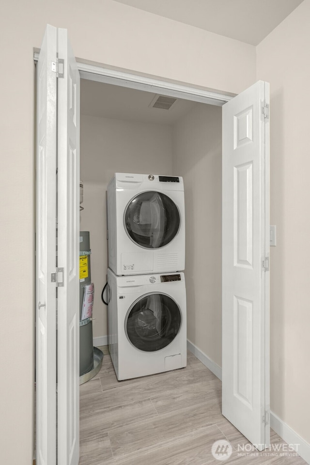 1319 E 56th St, Tacoma, WA 98404 - clothes washing area with estacked washer and dryer, secured water heater, baseboards, and wood finished floors