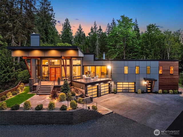 modern home with driveway, a chimney, and an attached garage