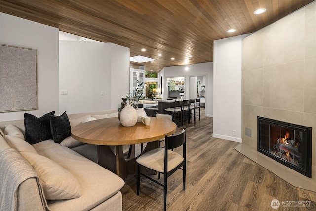 dining space featuring wooden ceiling, wood finished floors, recessed lighting, a tile fireplace, and baseboards