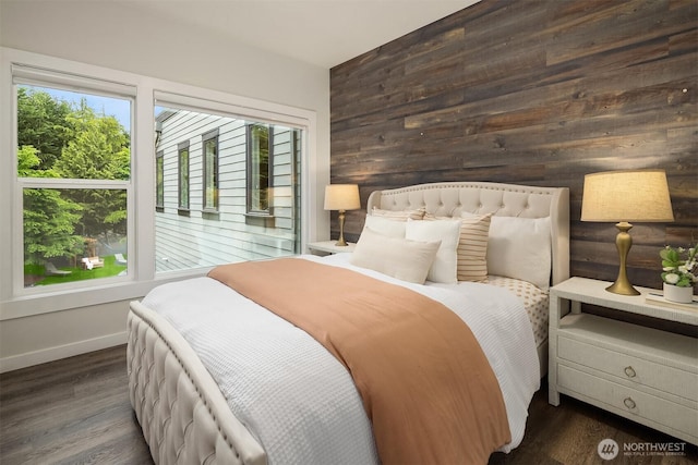 bedroom featuring baseboards, wood finished floors, and wooden walls