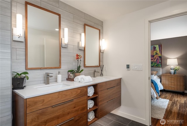 ensuite bathroom with double vanity, baseboards, and tasteful backsplash