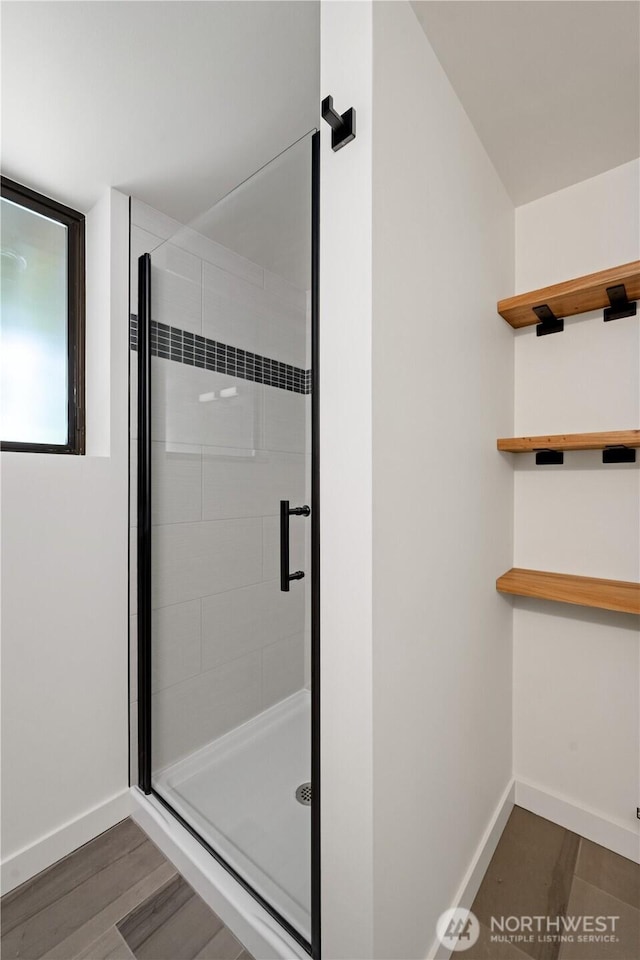 full bath featuring baseboards, a shower stall, and wood finished floors