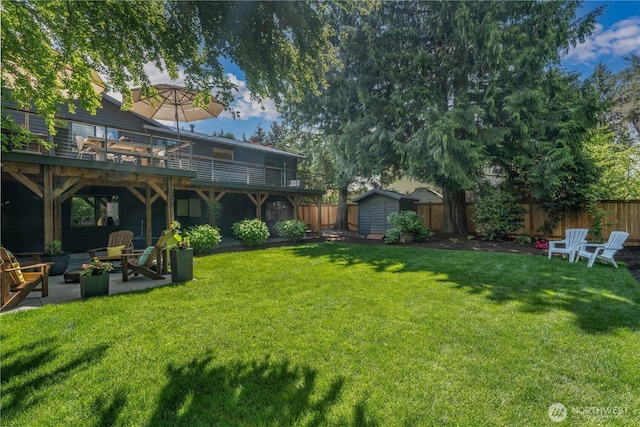 view of yard with a storage shed, an outdoor hangout area, an outdoor structure, a patio area, and a deck