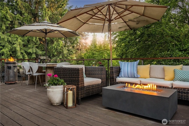 wooden deck with an outdoor living space with a fire pit and view of scattered trees