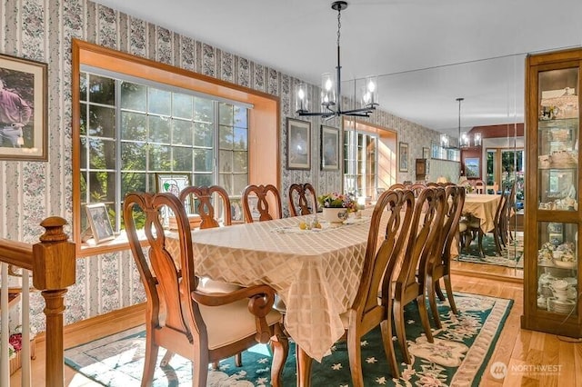 dining area featuring wallpapered walls, a chandelier, and hardwood / wood-style floors
