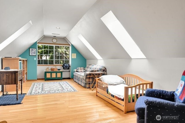 bedroom with wood finished floors, vaulted ceiling, and a skylight