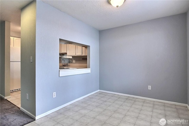 spare room with baseboards and a textured ceiling