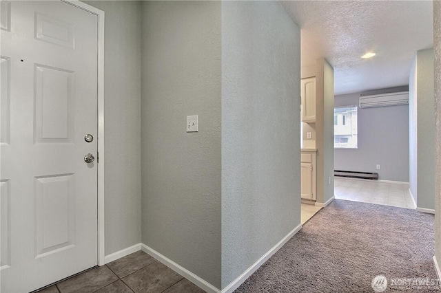 hall with a baseboard heating unit, light tile patterned floors, a wall mounted air conditioner, baseboards, and a textured ceiling