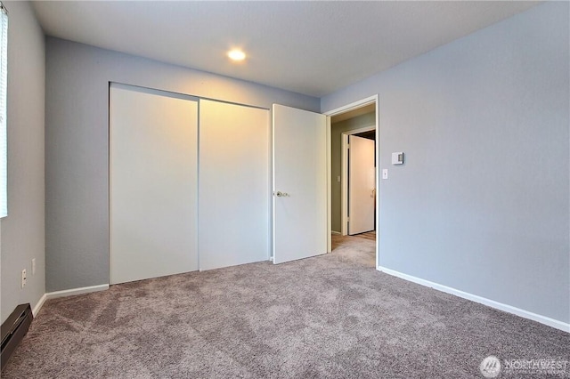 unfurnished bedroom with carpet, recessed lighting, a closet, a baseboard radiator, and baseboards