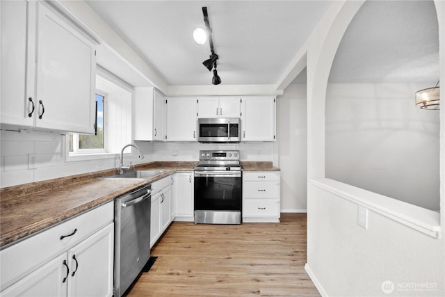 10320 16th St E, Edgewood, WA 98372 - kitchen with stainless steel appliances, a sink, white cabinetry, backsplash, and light wood-style flooring
